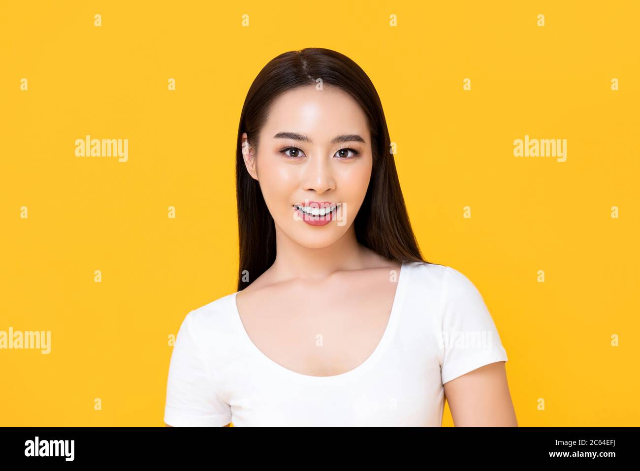 Glücklich lächelnd lange Haare schöne asiatische Frau Blick auf Kamera isoliert auf gelbem Hintergrund Stockfoto