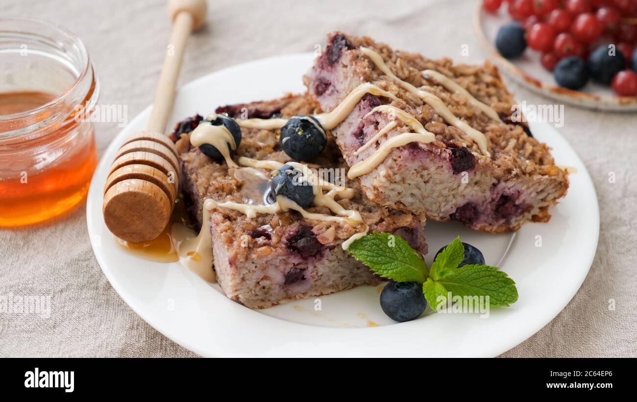 Vegetarisch gebackener Haferflocken mit Heidelbeer oder Haferproteinriegel serviert mit Nussbutter. Nahaufnahme. Gesundes Frühstück Stockfoto