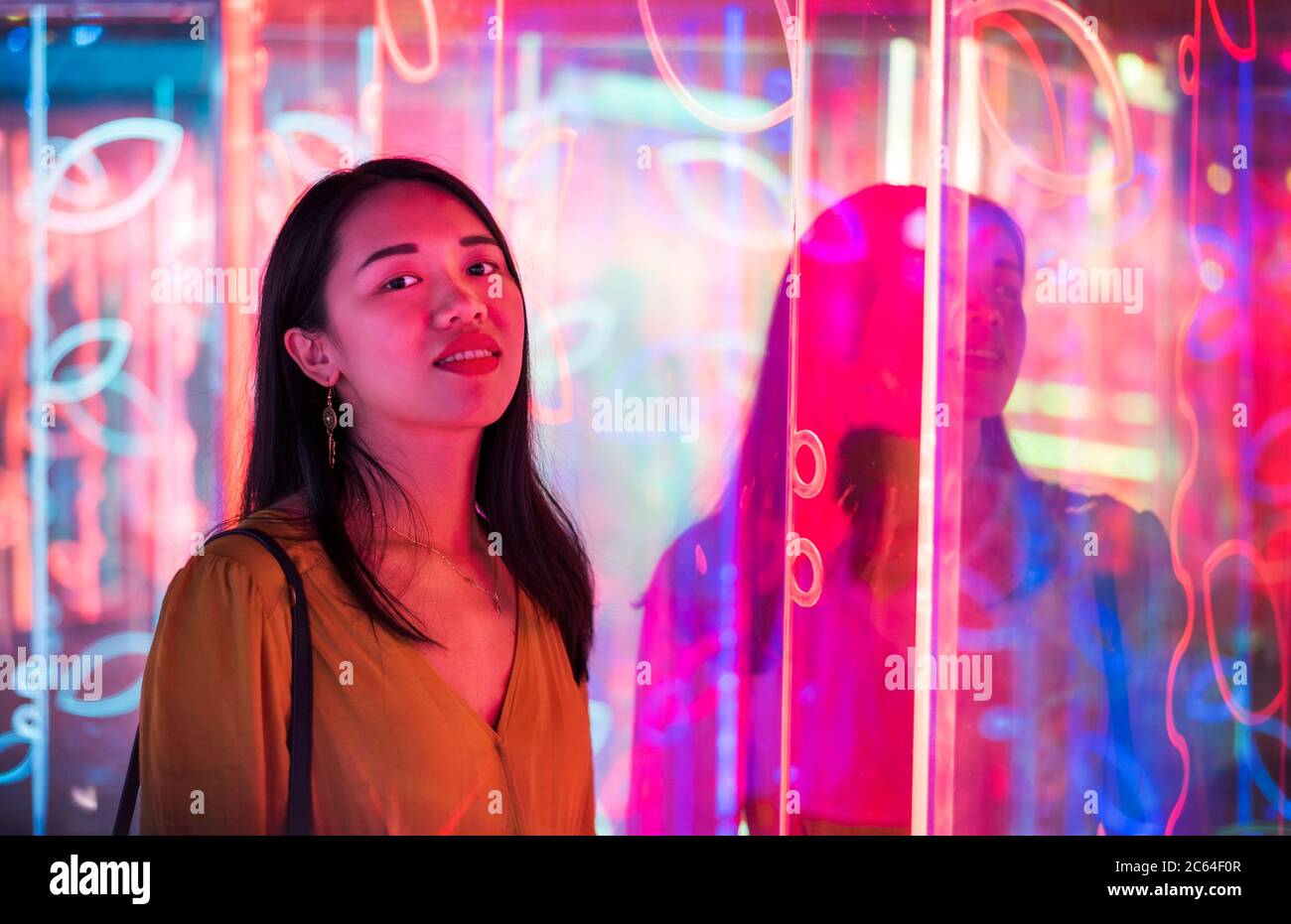 Asiatische Frau Porträt beleuchtet von Neon beleuchteten Spiegeln in der Nacht Stockfoto