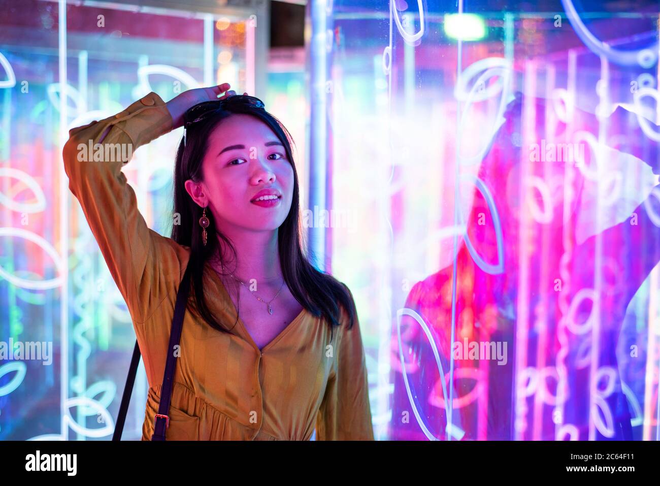 Asiatische Frau Porträt beleuchtet von Neon beleuchteten Spiegeln in der Nacht Stockfoto