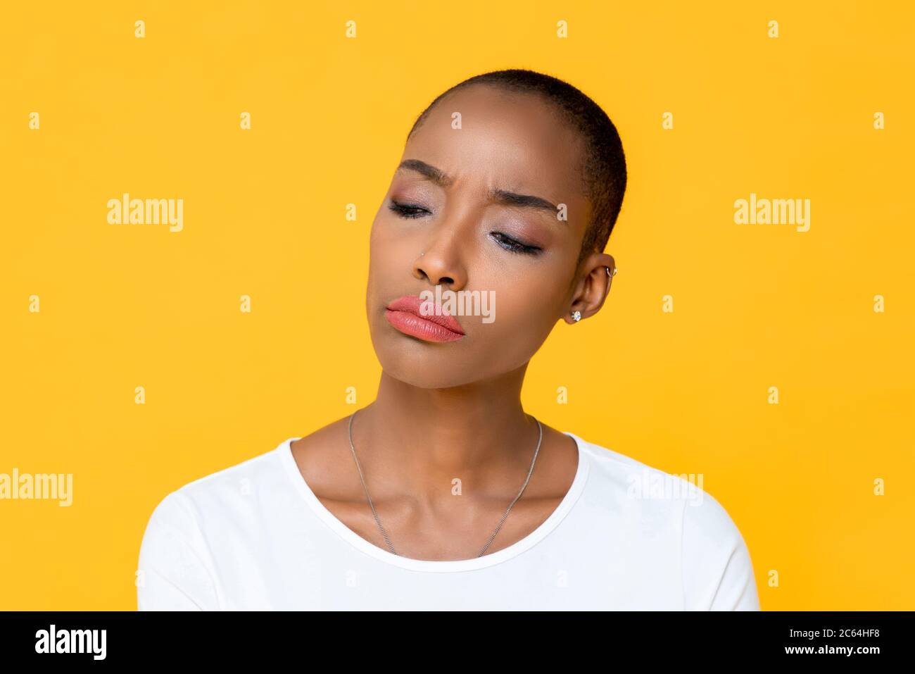 Nahaufnahme Porträt unglücklicher junger afroamerikanischer Frau denken, die sich gelangweilt und aufgeregt in isolierten Studio gelben Hintergrund Stockfoto