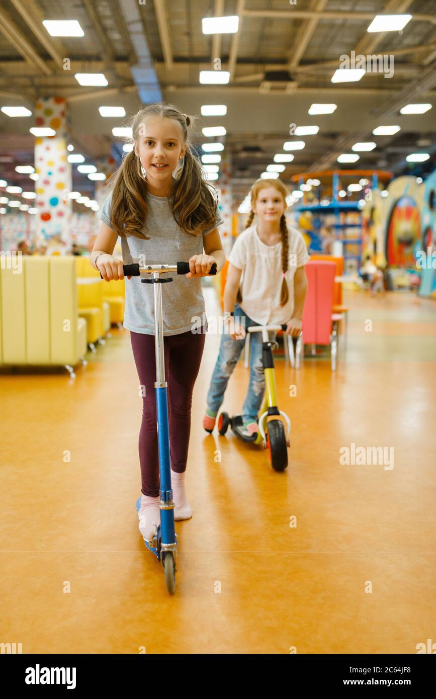 Kleine Freundinnen fahren auf Roller, Spielplatz Stockfoto