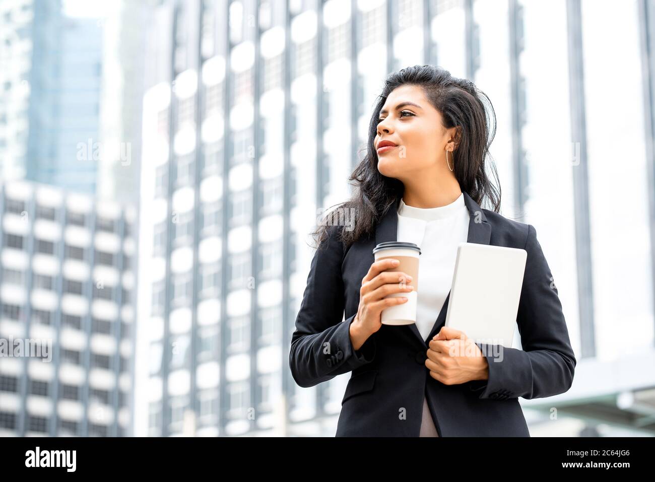 Porträt von schönen jungen zuversichtlich hispanischen Geschäftsfrau, die eine Kaffeepause halten Tablet in der Stadt Hintergrund Stockfoto