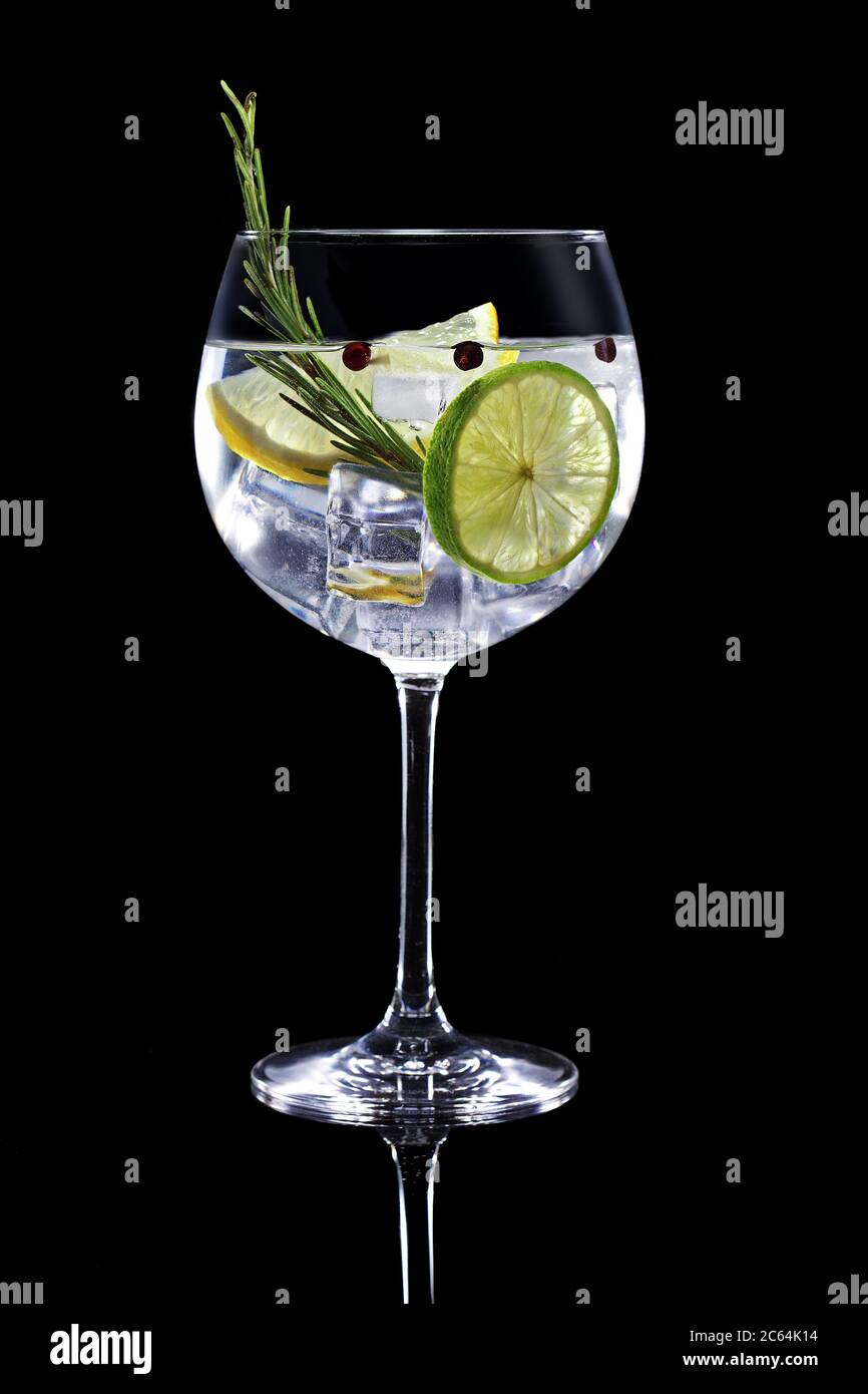 gin Tonic garniert mit Zitrusfrüchten und Rosmarin isoliert auf schwarzem Hintergrund Stockfoto