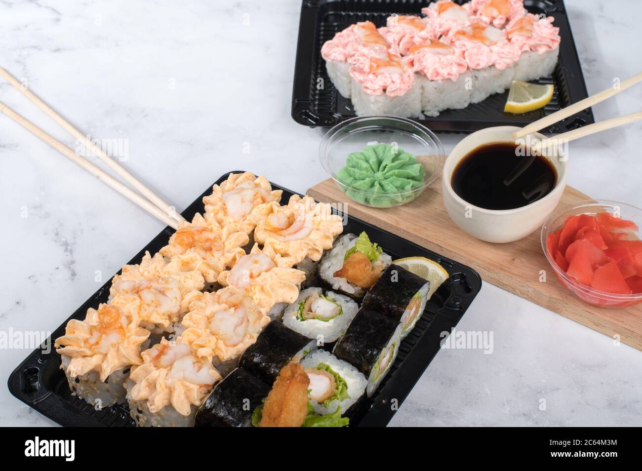 Sushi-Brötchen auf dunklem Holzbrett mit Wasabi, Sojasauce und Ingwer. Grauer Hintergrund Stockfoto