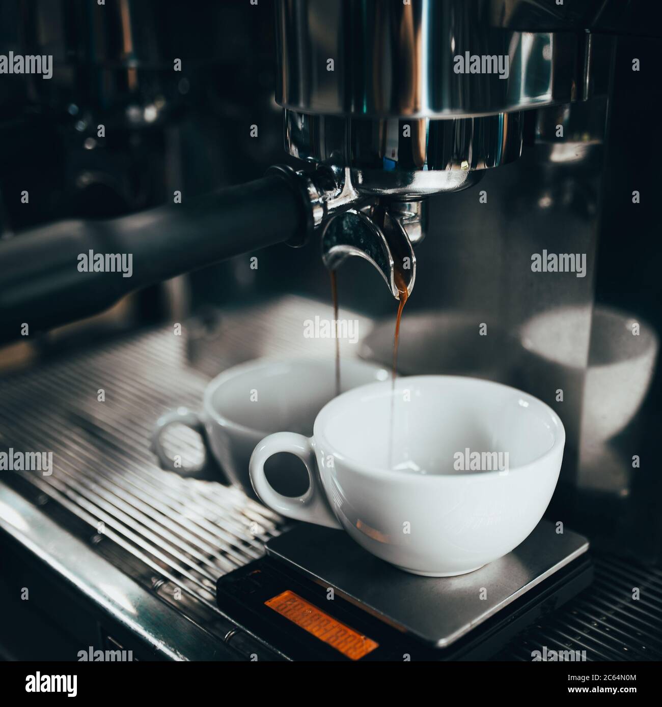 Espresso tropft in einem dünnen Strahl aus einer Kaffeemaschine in eine  weiße Tasse - Kaffee in einer Bar und einem Café zubereiten Stockfotografie  - Alamy