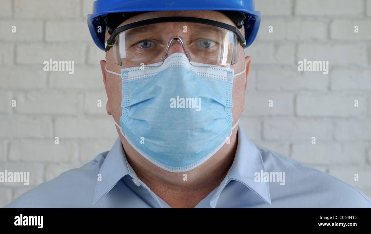 Ingenieur mit Sicherheitshelm und Schutzmaske auf seinem Gesicht im Gespräch mit dem Handy Stockfoto
