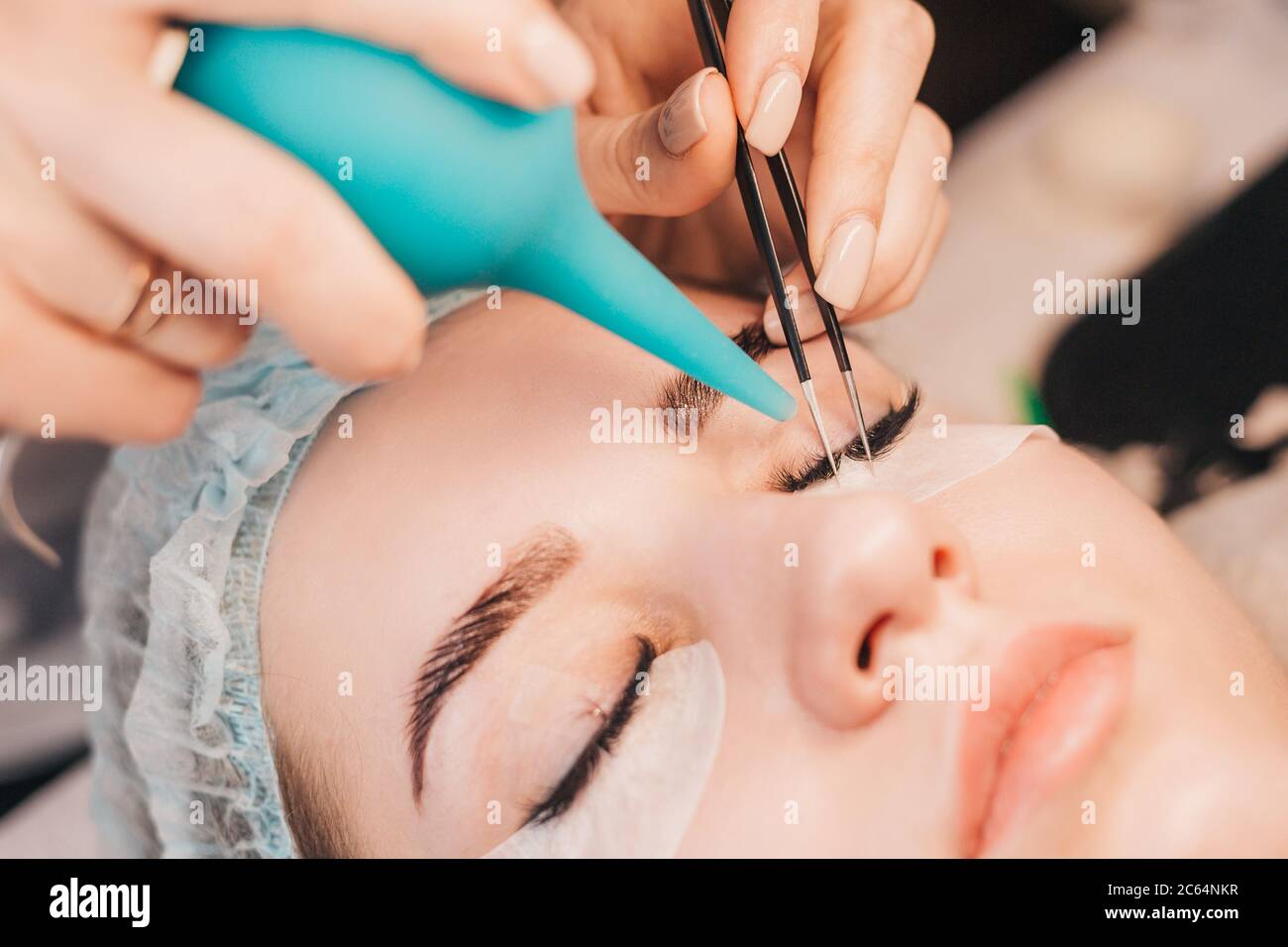 Wimpernverlängerungen - der Meister trocknet den Leim mit der Luft - sorgfältig filigrane Arbeit Stockfoto