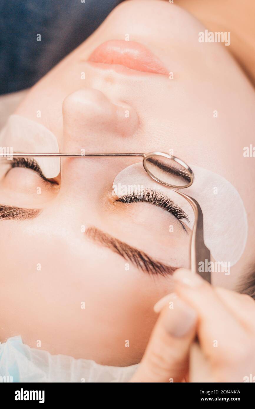 Wimpernverlängerungen - der Meister trocknet den Leim mit der Luft - sorgfältig filigrane Arbeit Stockfoto