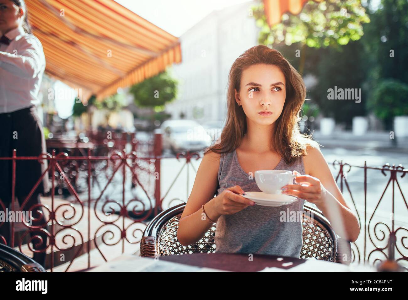 Minsk, Weißrussland - 19. Juni 2020: Schlanke kaukasische elegante Frau mit einer Tasse Tee am frühen Morgen in einem Café ein verträumter Blick - romantische Stimmung Stockfoto