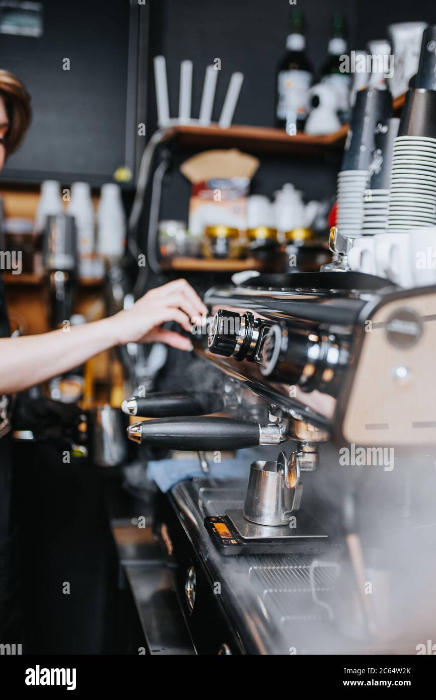 Barista Mädchen bei der Arbeit in einem Café - Kaffeemaschine mit Dampf Stockfoto