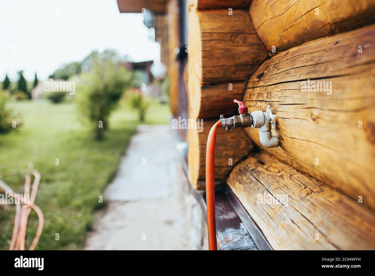 Der Abschluss der Wasserleitung durch die Wand des Hauses aus einem Log für  den Anschluss eines Bewässerungsgartenschlauch Stockfotografie - Alamy