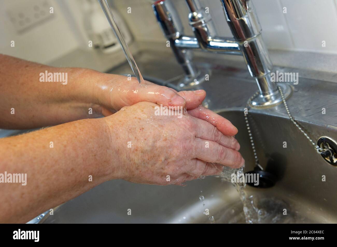Eine weibliche Person, die sich unter fließendem Leitungswasser die Hände wäscht. Stockfoto