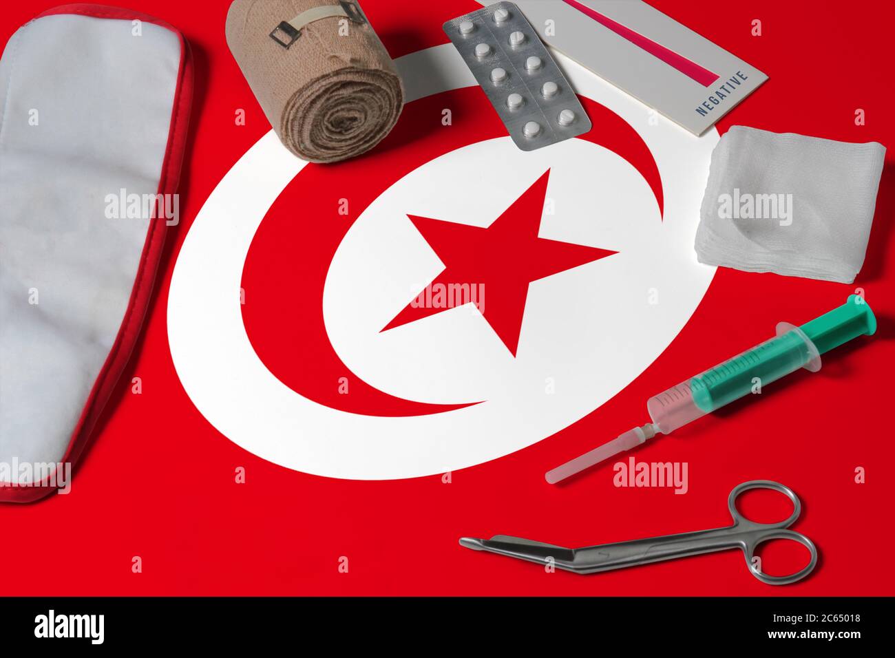 Tunesien Flagge mit erste-Hilfe-medizinischen Kit auf Holztisch Hintergrund. Nationales Gesundheitssystem Konzept, medizinisches Thema. Stockfoto