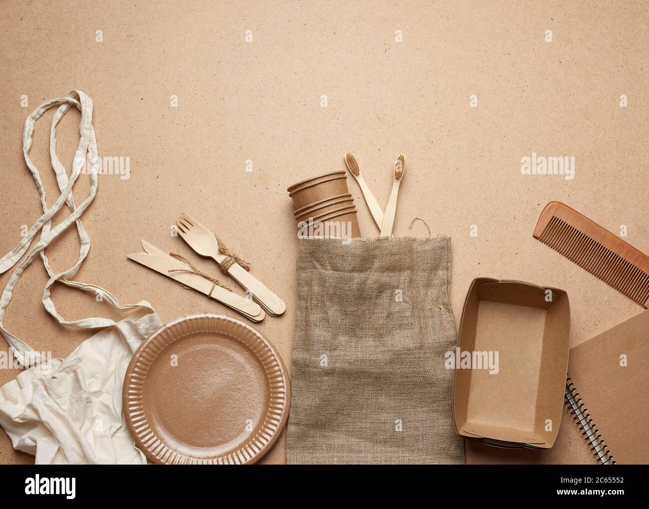 Weiße Stofftasche und Einweggeschirr aus braunem Bastelpapier auf braunem Holzhintergrund. Blick von oben, Kunststoff-Ausschusskonzept, keine Verschwendung Stockfoto