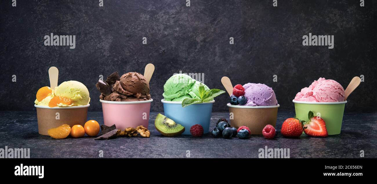Verschiedene bunte Eis in Papierbecher auf dunklen rustikalen Hintergrund Stockfoto