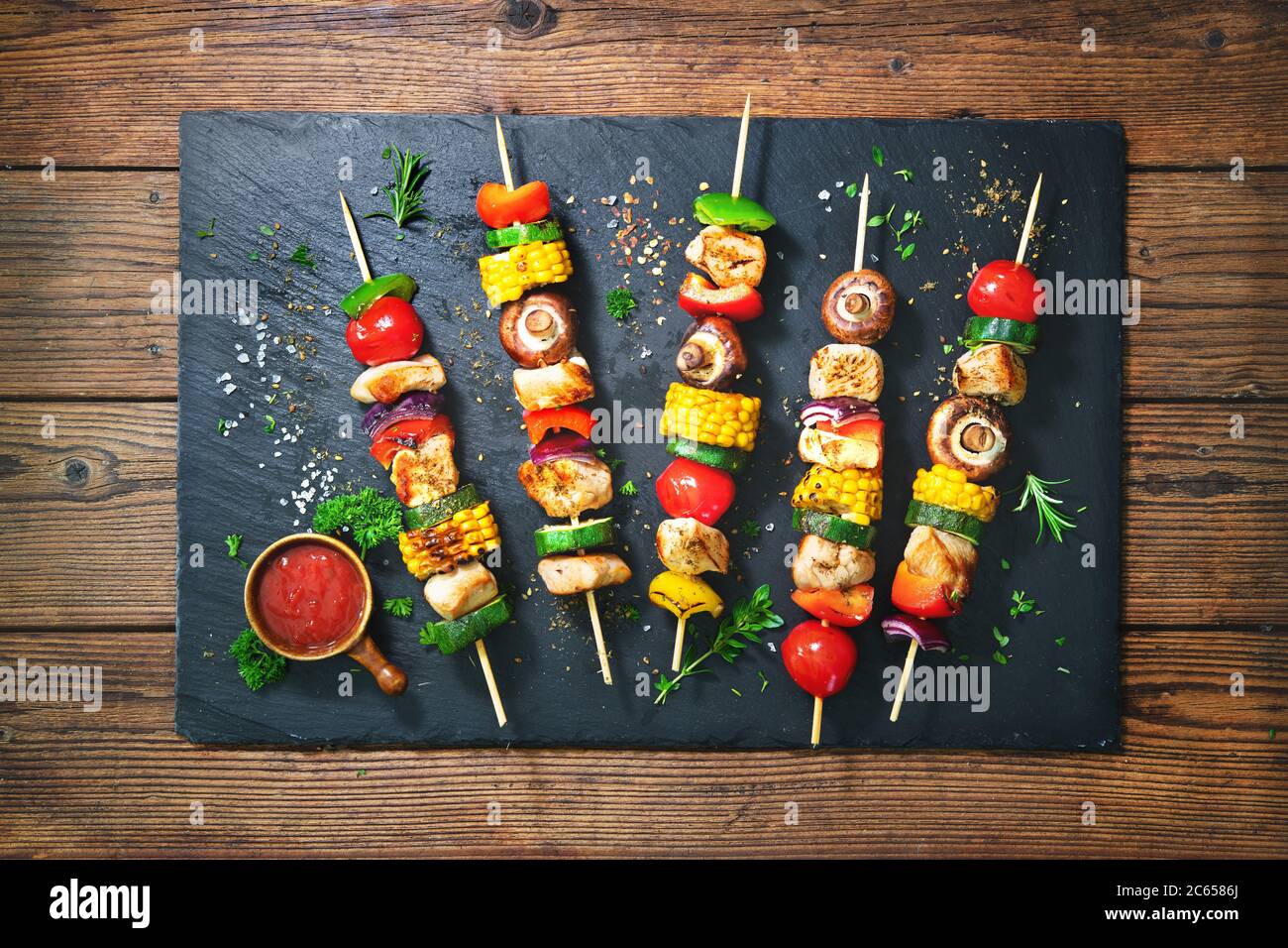 Hühnerkebabs auf Spieße mit Pilzen und Gemüse auf Schieferplatte Stockfoto