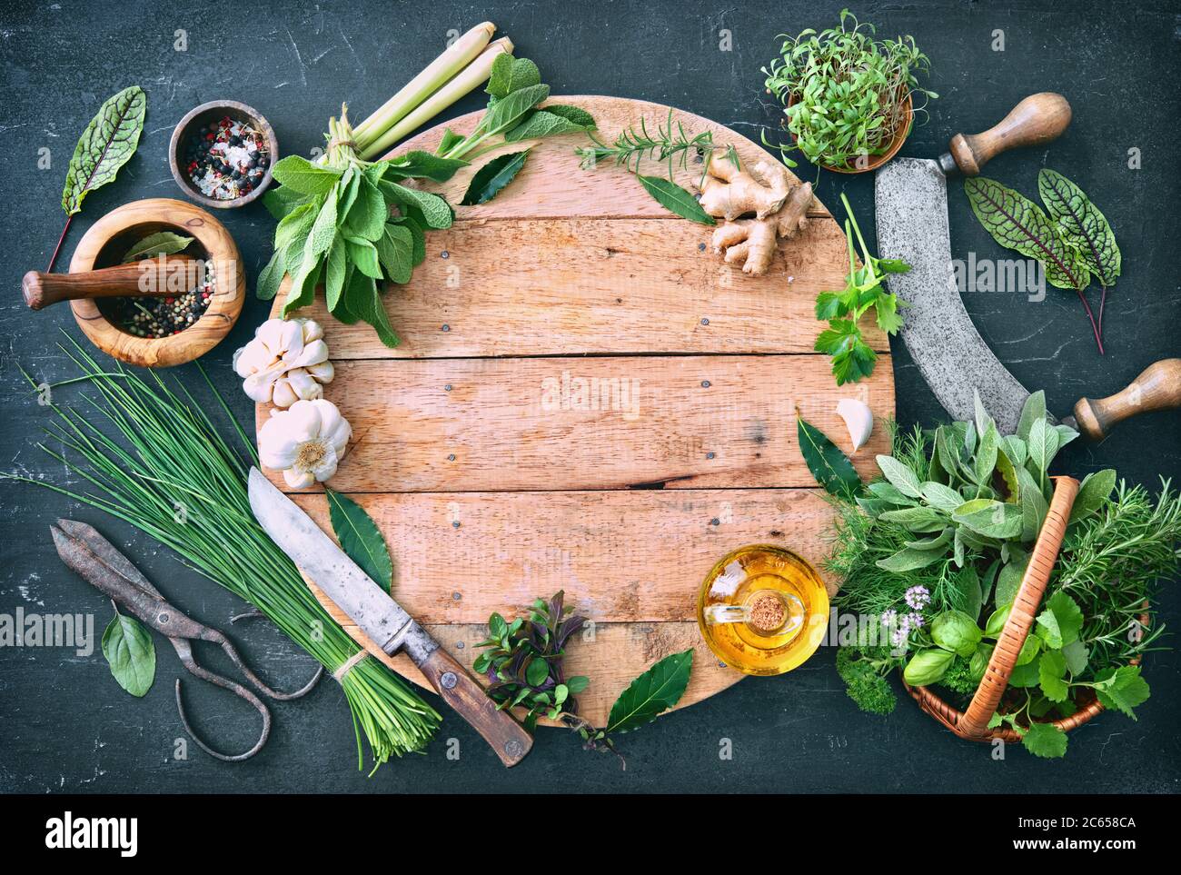 Verschiedene frische Kräuter aus dem Garten mit Küchenutensilien auf rustikalem Tisch. Draufsicht mit Kopierbereich Stockfoto