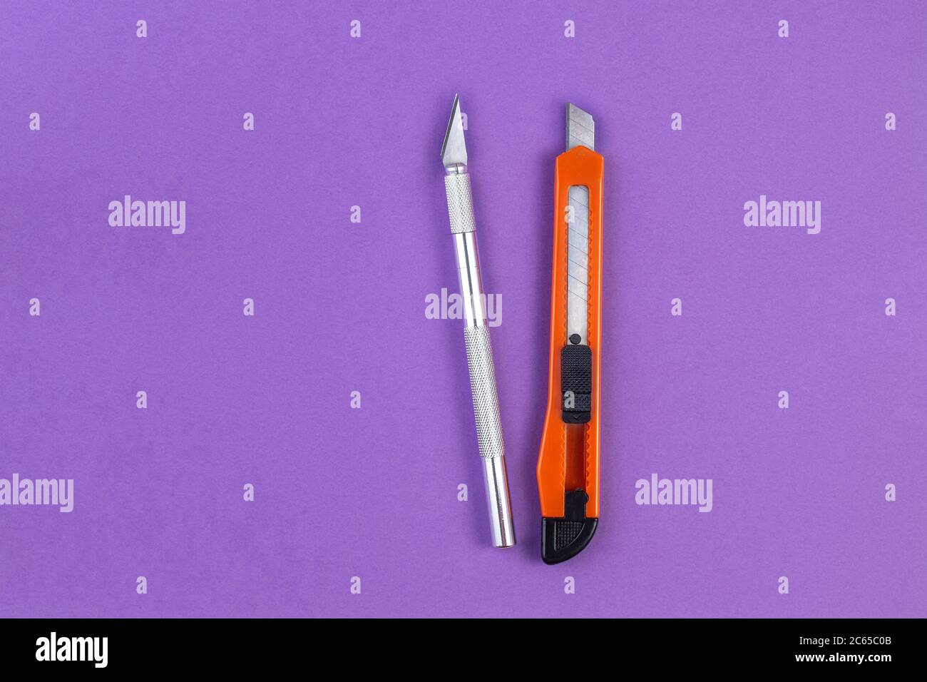 Schreibwarenmesser und Papiermesser auf violettem Papierhintergrund. Schulbüro liefert mit Kopierplatz. Zurück zur Schule Konzept. Stockfoto