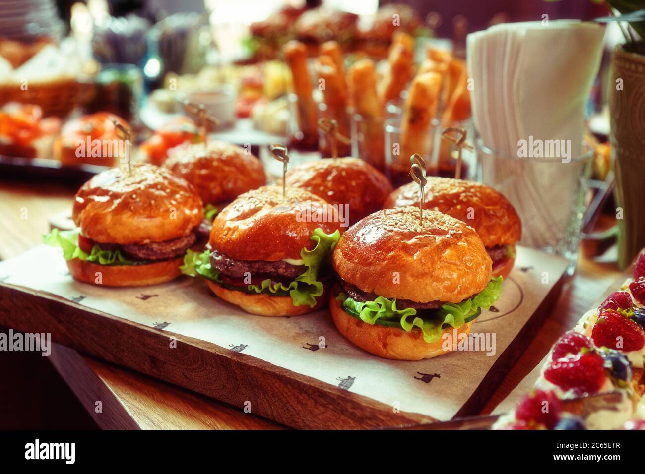 Burger und ein weiteres Essen auf Restauranttisch, Catering-Veranstaltung, getönte Stockfoto