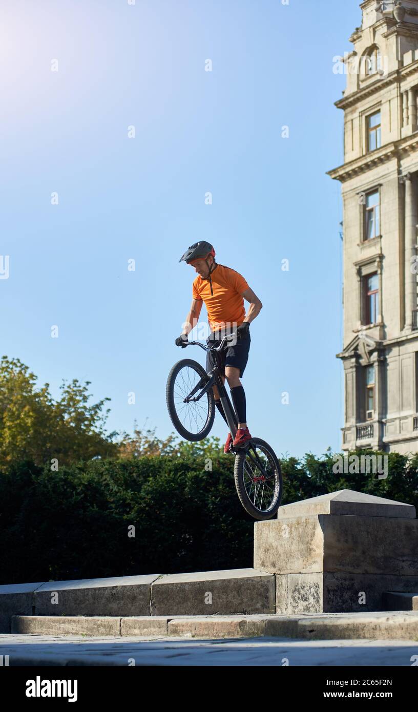 Trial Biker steht auf dem Hinterrad seines Mountainbikes an einem schönen sonnigen Tag über blauem Himmel, Konzept des aktiven Lebensstils Stockfoto
