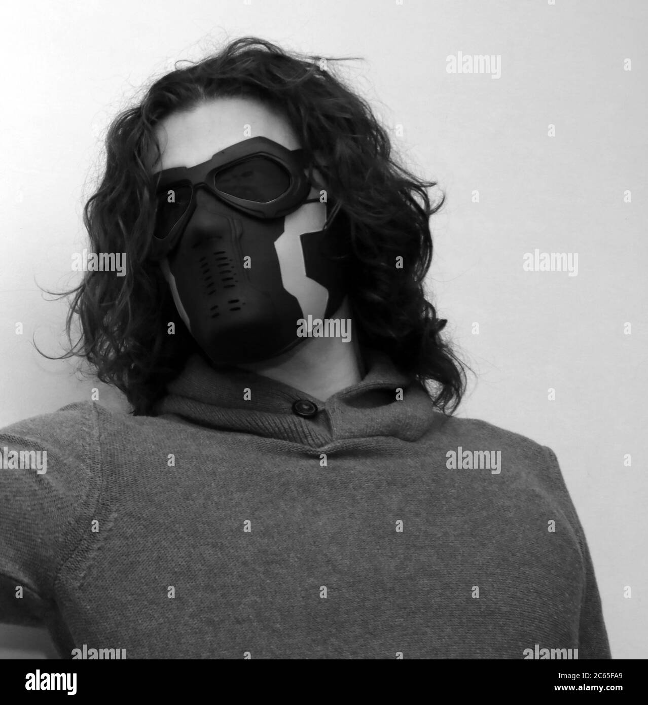 Attraktive lockige Kerl mit Maske posiert im Studio auf isolierten Hintergrund. Maskerade, halloween, Sci-Fi Konzept. Stockfoto
