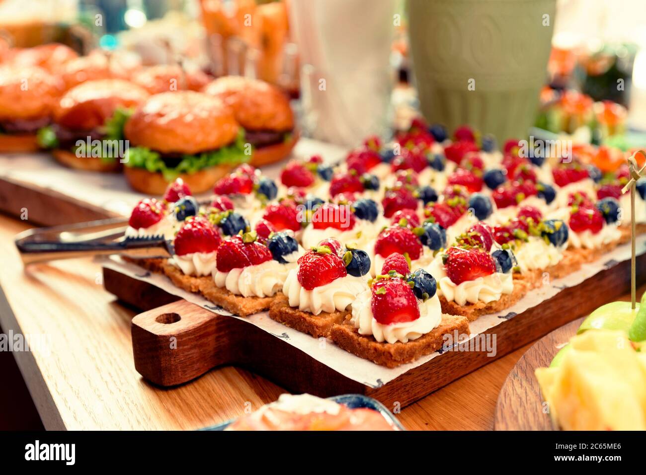 Desserts und Burger auf dem Tisch, Hotel Dinner Board, getönte Stockfoto