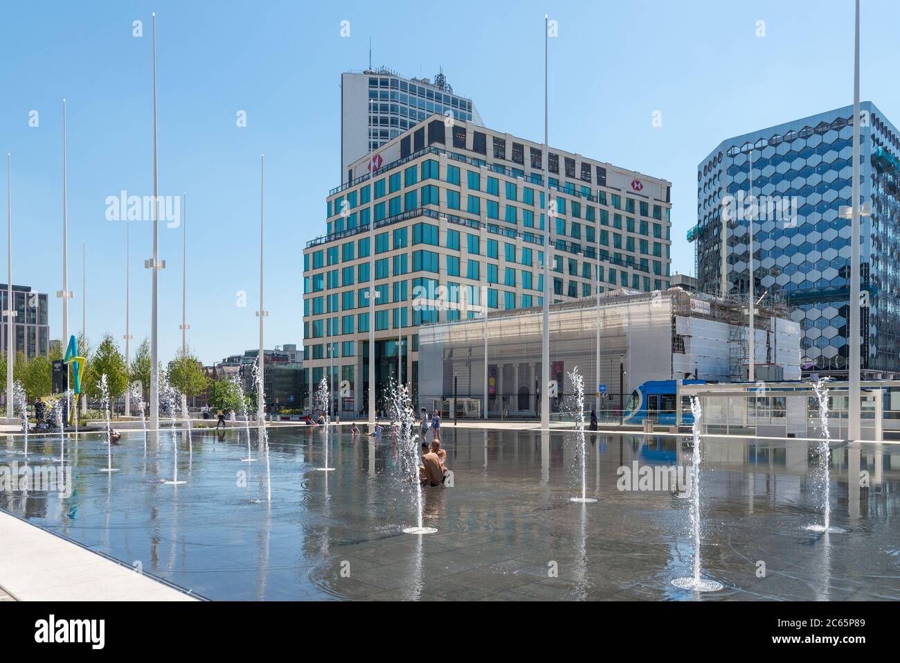 Menschen, die sich in den Wasserfontänen im Wasserspiegel am Centenary Square, Birmingham, Großbritannien, abkühlen Stockfoto