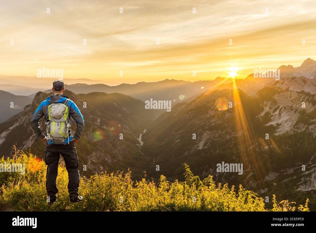 Mann erreicht Gipfel genießen erstaunliche Sonnenaufgang in den Bergen. Hintergrundbeleuchtung Sonnenlicht mit schönen Fackeln und Sonnenstrahlen. Die Julischen Alpen, Triglav Stockfoto