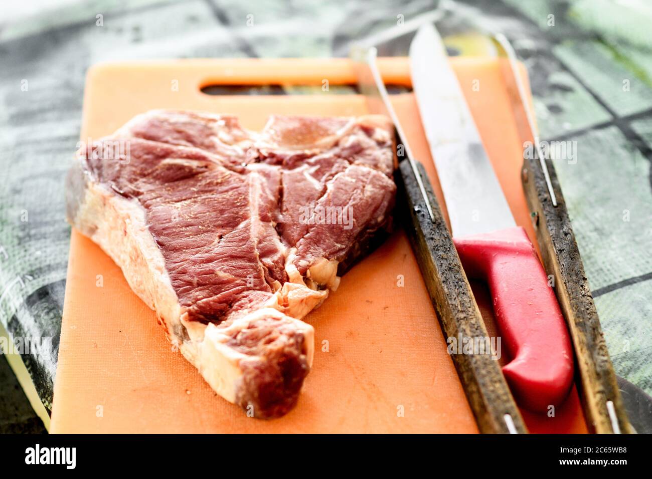 Rohes Florentiner Rindersteak auf einem Schneidebrett mit Küchenmessern, die bereit sind, in einer hohen Winkel-Nahaufnahme zu kochen Stockfoto