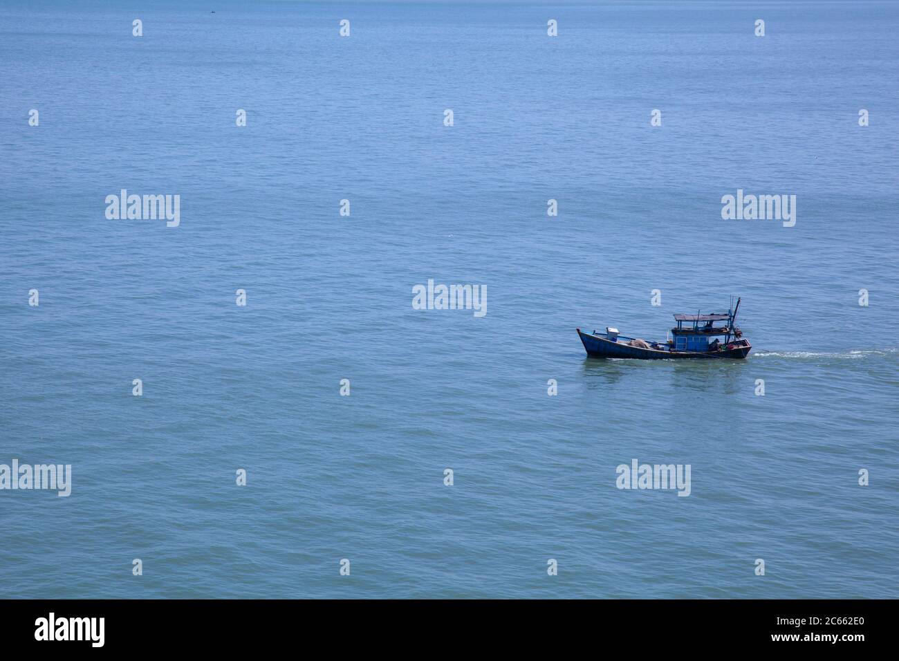 Einsames blaues Fischerboot auf einem weiten ruhigen Meer ohne anderes Motiv in der Szene auf dem Südchinesischen Meer in der Nähe von Vietnam. Stockfoto