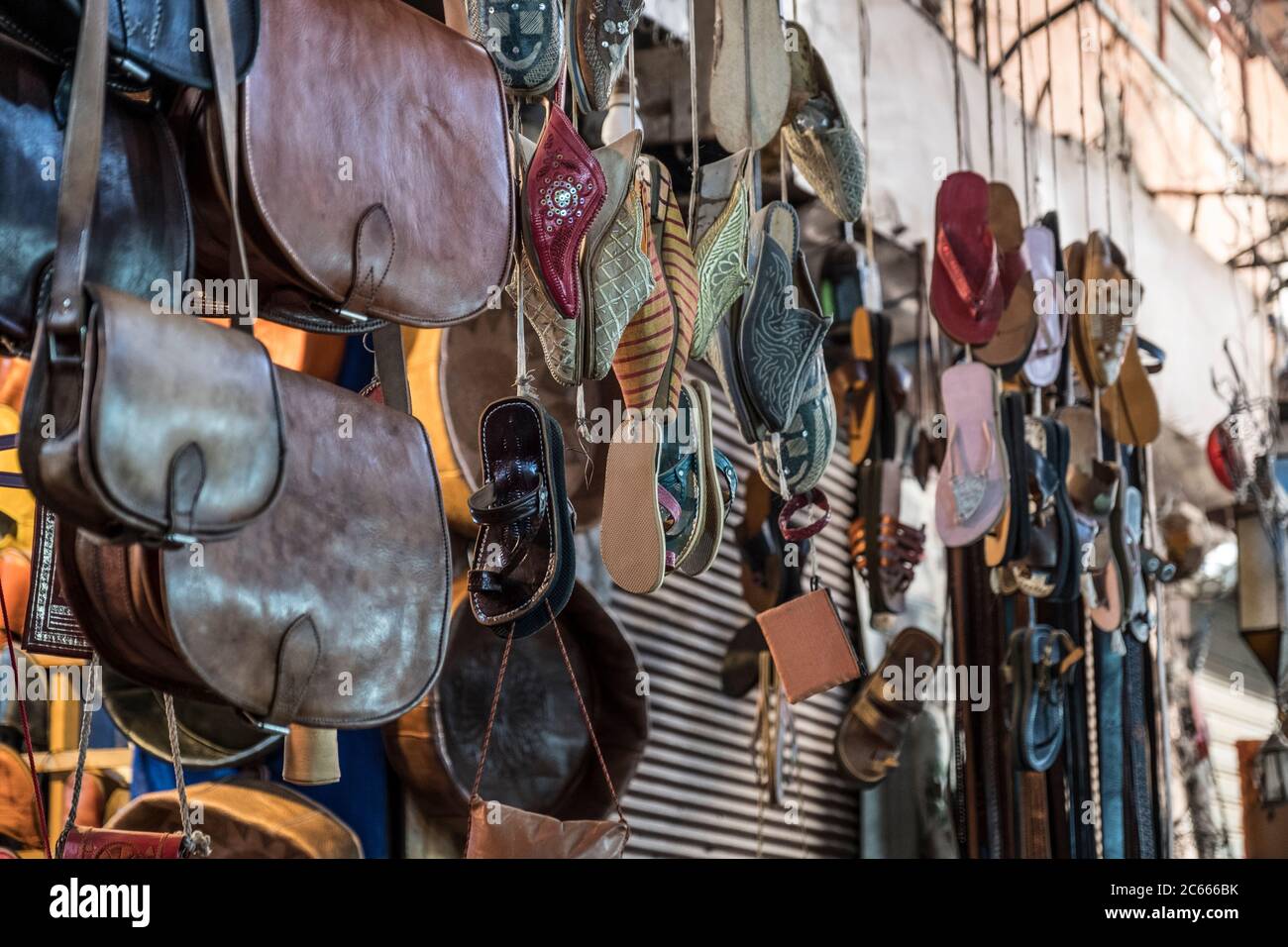 Ledertaschen und Sandalen hängen in einem Souk in Marrakesch, Marokko Stockfoto