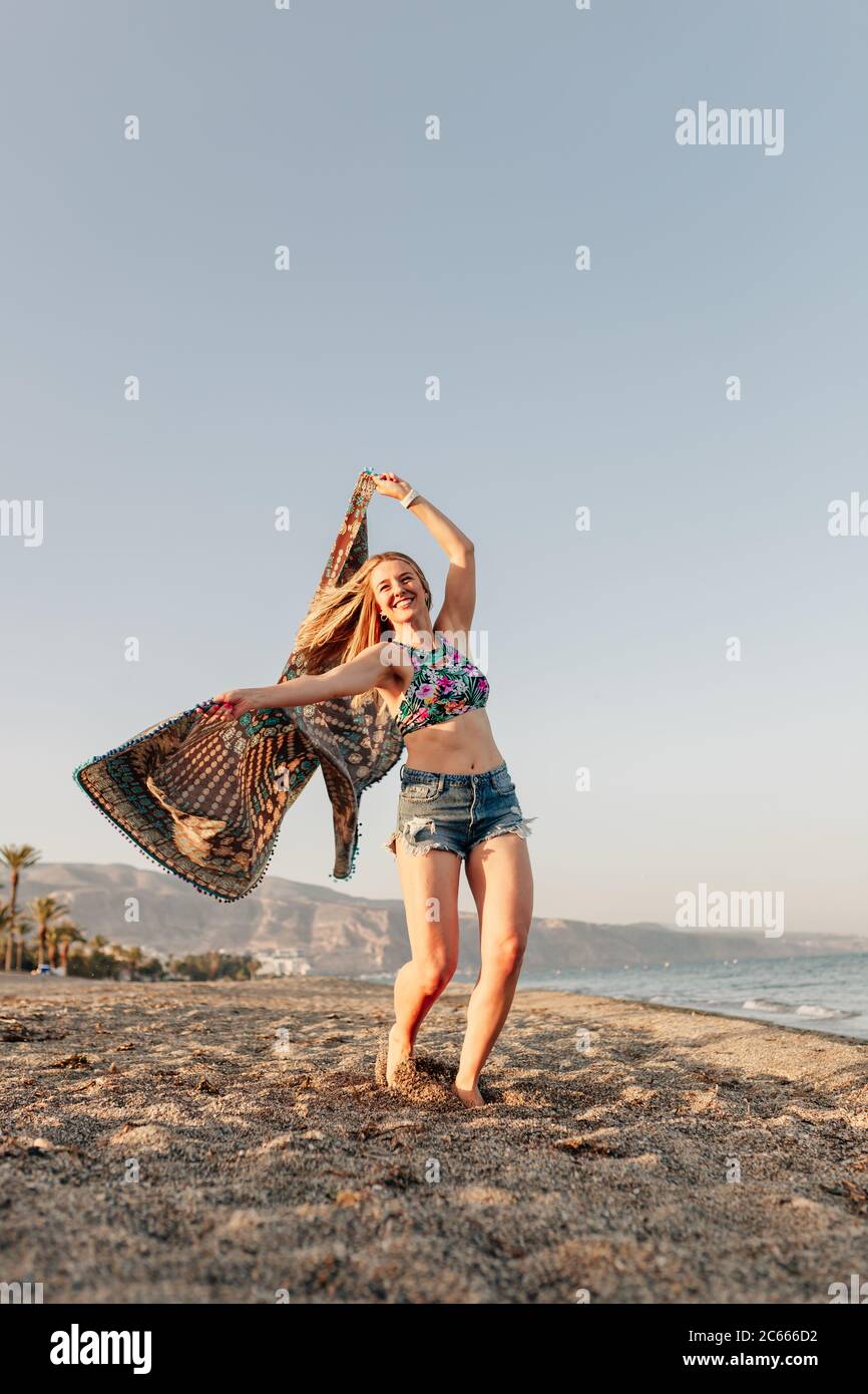 Frau läuft und hält Schal auf Welle entspannen und glücklich am Strand Stockfoto