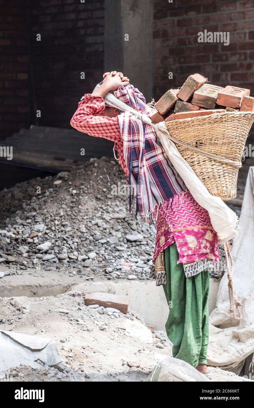 Baustelle mit Frau, die Steine trägt in Swayambhunath bei Kathmandu in Nepal Stockfoto