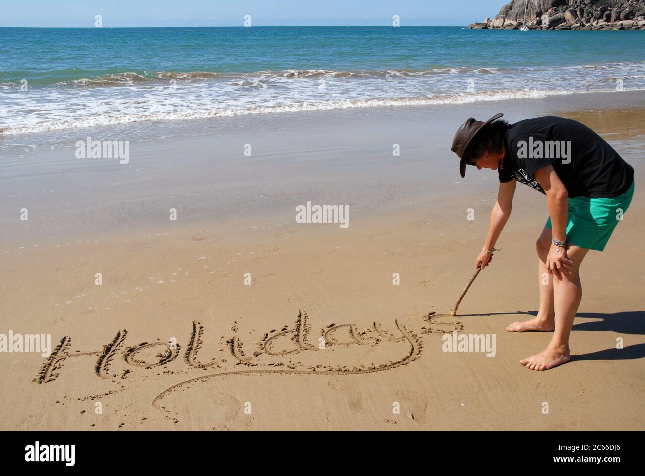 Frau, die das Wort schreibt Urlaub im Sand am Strand von Radical Bay, Magnetic Island, Queensland, Australien Stockfoto