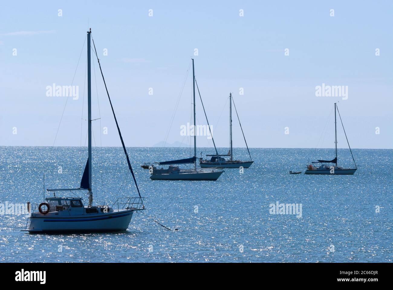 Contre jour Bild von Yachten vor Anker Horsehhoe Bay, Magnetic Island, an einem ruhigen und ruhigen Nachmittag mit Sonnenlicht auf dem Wasser und Palm Island auf der Stockfoto