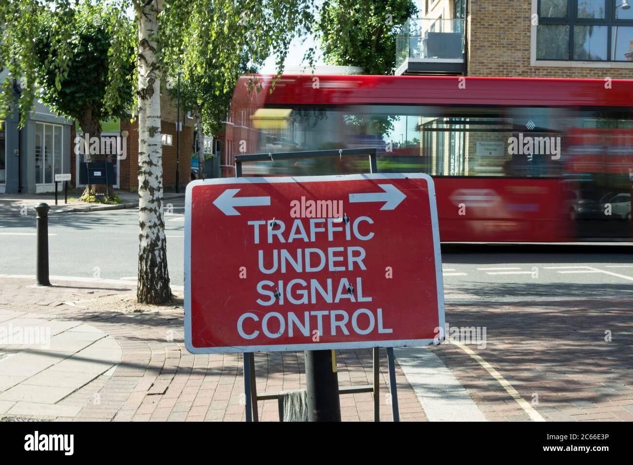 Verkehrszeichen, das den Verkehr auf der Straße anzeigt, die vor uns liegt, und unter Signalkontrolle steht, in twickenham, middlesex, england, mit vorbeifahrenden Bussen, die in unscharfer Bewegung gesehen werden Stockfoto