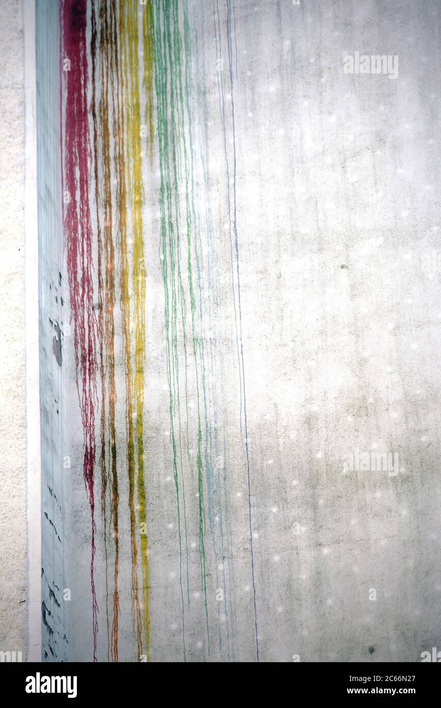 Die bunten Streifen und Blobs blutender Farbe auf einer Betonfassade, Stockfoto