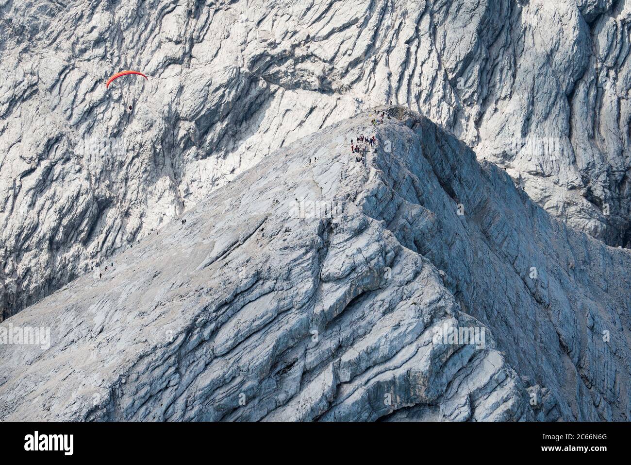 Alpspitze Peak mit Bergsteigern und Gleitschirm, Hochblassen im Hintergrund, Luftaufnahme, Garmisch-Partenkirchen, Bayern, Deutschland Stockfoto