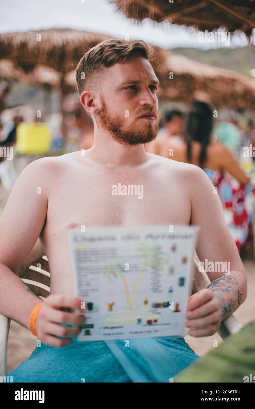 Junger Mann wartet auf eine Kellnerin an der Strandbar Stockfoto