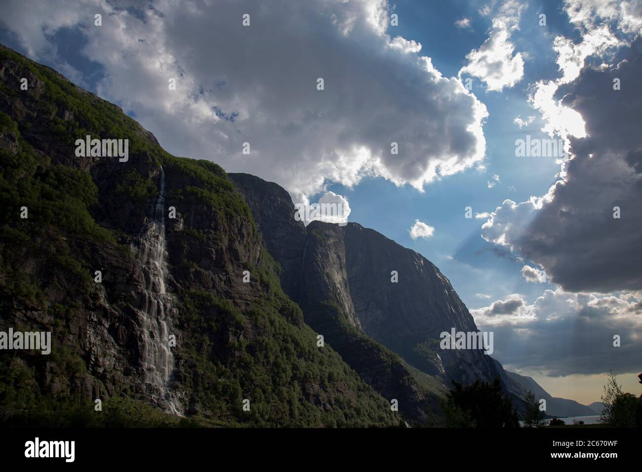 Abends ein schöner Fjord-Talblick, umgeben von Bergen, bewölktem blauem Himmel. Stockfoto