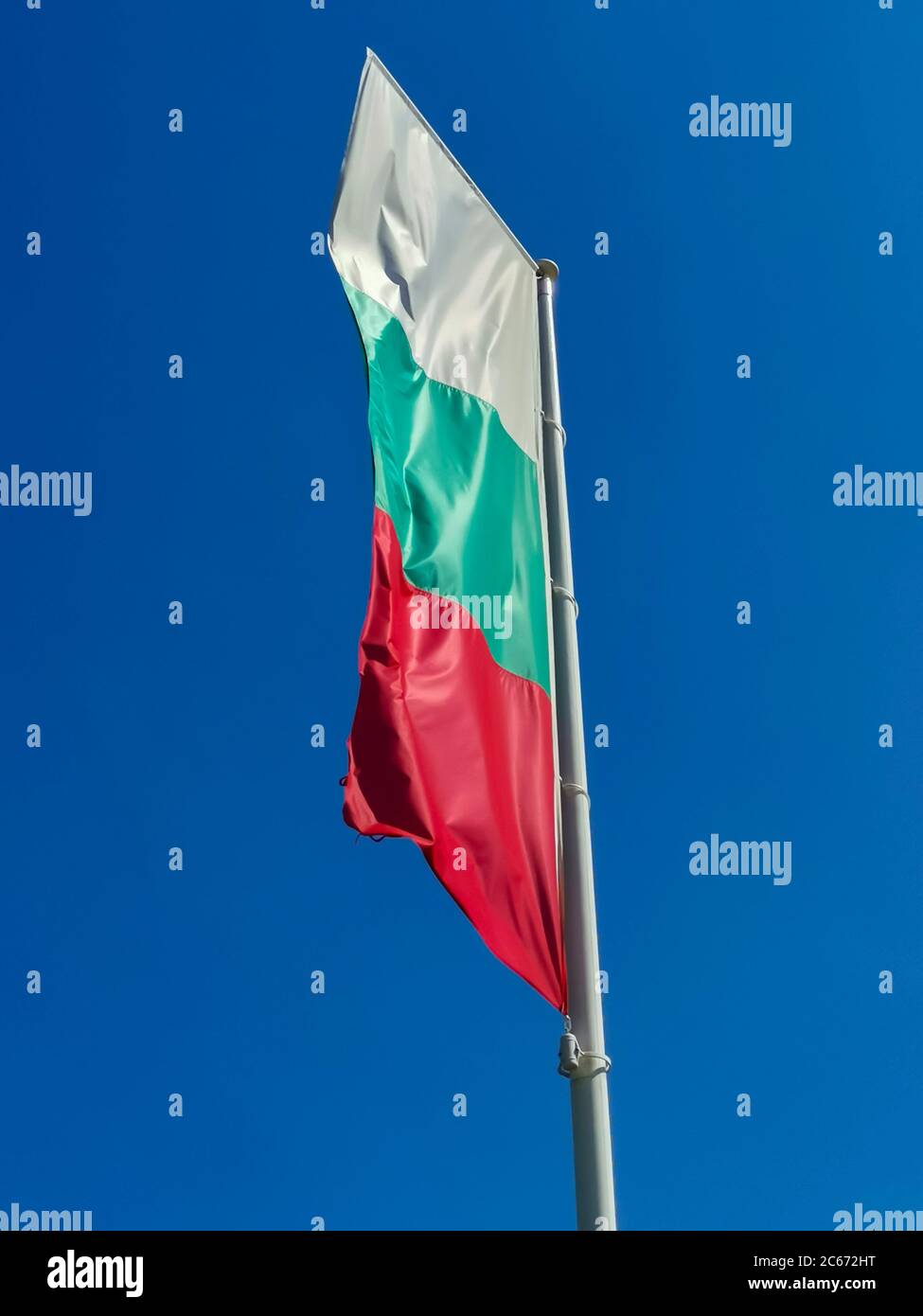 Bulgarische Flagge winkt auf blauem Himmel Hintergrund. Der Standort ist Obzor, Bulgarien. Flagge Bulgariens gegen den klaren Himmel. Stockfoto