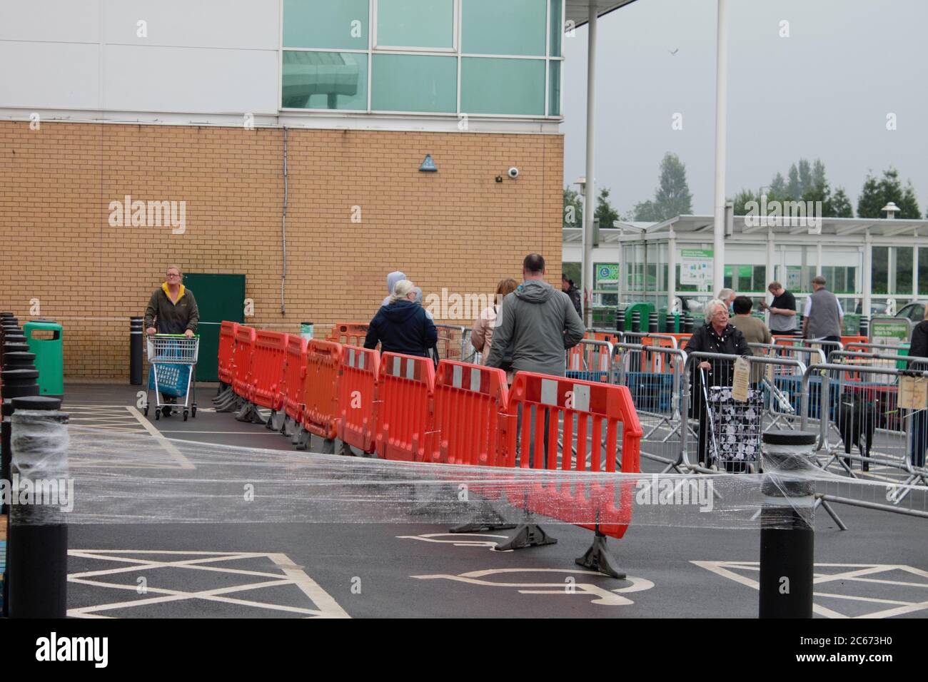 Menschen soziale Distanzierung in einer Warteschlange, um einen Supermarkt zu betreten Stockfoto