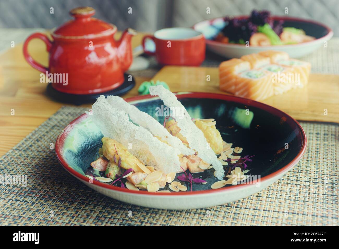 Maki-Brötchen, gebratene Garnelen und Tee auf dem Tisch, japanisches Restaurant, getönte Stockfoto