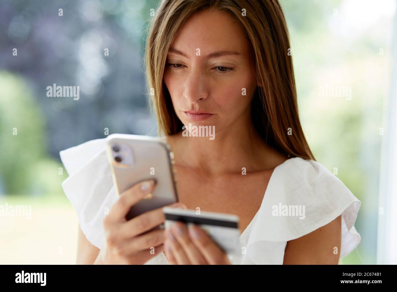 Frau, die auf ihr Telefon und ihre Kreditkarte schaut Stockfoto