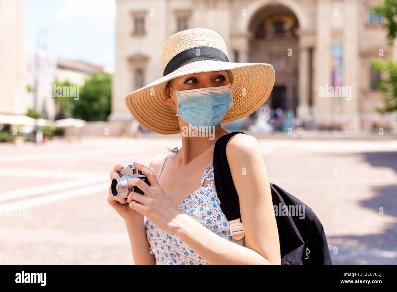 Portrait Aufnahme der schönen blonden Frau trägt Gesichtsmaske zur Prävention, während mit der Kamera, um Fotos in der Stadt. Stockfoto