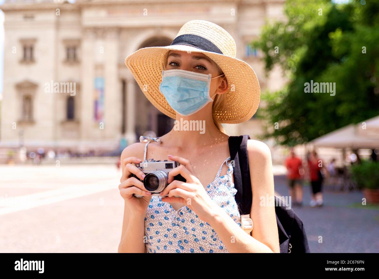 Portrait Aufnahme der schönen blonden Frau trägt Gesichtsmaske zur Prävention, während mit der Kamera, um Fotos in der Stadt. Stockfoto
