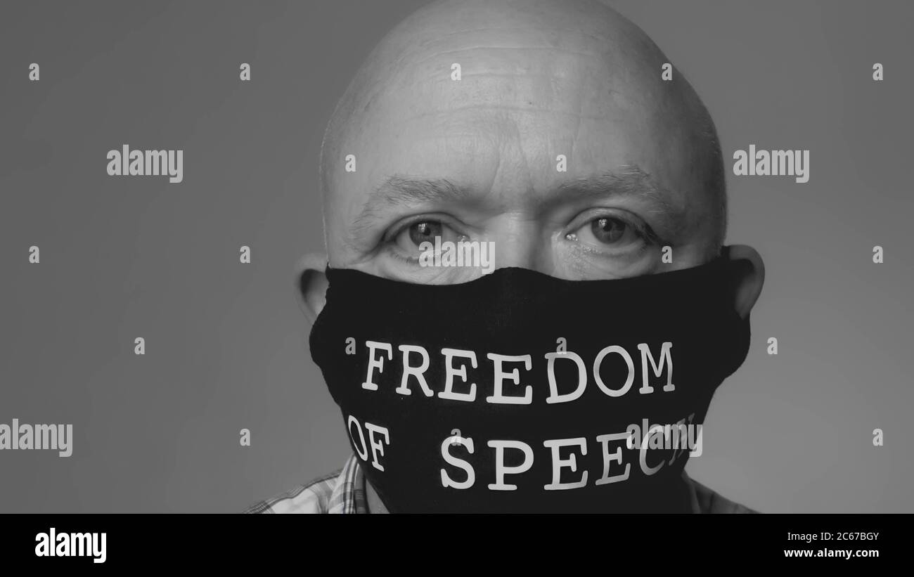 Kahlköpfiger Mann mittleren Alters trägt eine Gesichtsmaske, auf der die Worte Redefreiheit ironisch gedruckt sind Stockfoto