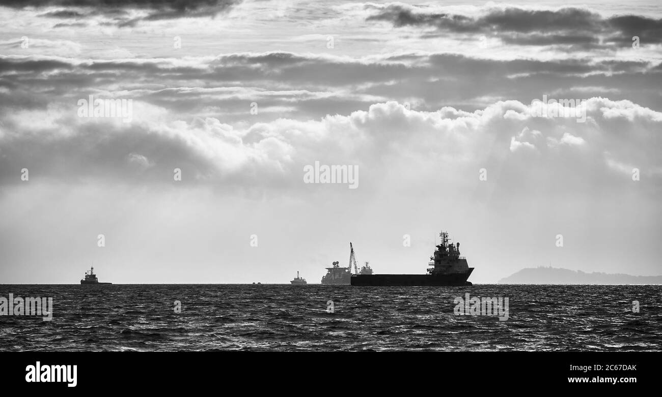 Schwarz-Weiß-Bild von Schiffen Silhouetten am Horizont bei Sonnenuntergang. Stockfoto