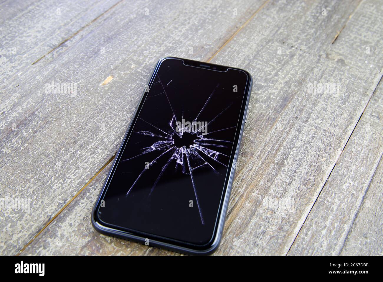 Viersen, Deutschland - 6. Juli. 2020: Nahaufnahme eines isolierten Mobiltelefons mit zerrissenem Glasdisplay auf Holztisch Stockfoto